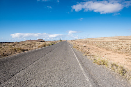 travel concept with a beautiful landscapes in Fuerteventura. Desert with a long road desolated in the middle. Easy life enjoying the natureの写真素材