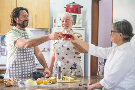 3-person family toasting with red wine while preparing dishes prepared in the home kitchenの写真素材