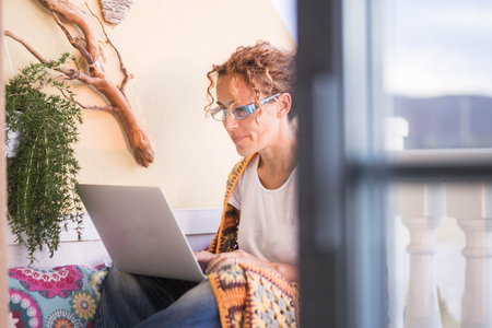 free work style lifestyle independent for cute beautiful caucasian woman work and write a book at laptop on the terrace outdoor at home. modern kind of work concept.の写真素材