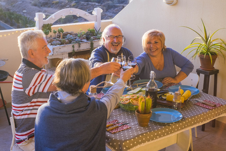 adult group of people having nice dinner outdoor in the terrace. enjoy the friendship with time together drinking and celebrating holiday or retired concept. sunny night sunset, sit down with joy near the tableの写真素材