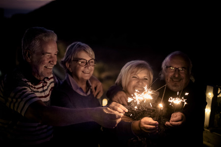Two senior couples celebrate dinner on the rooftopの写真素材