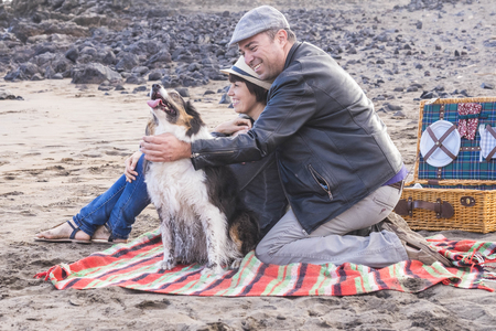 freedom and leisure pic nic activity on the beach for an alternative family group of friends two person and a nice dog. everybody have fun outdoor in vacationの写真素材