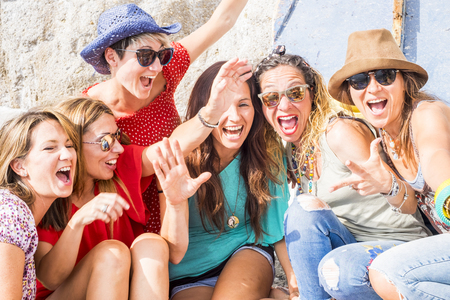 group of crazy nice beautiful caucasian girls outdoor under the summer sun doing a party all together. people having fun iall together oncept lifestyle. shout and laugh full of joyful womenの写真素材