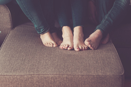 three woman nude feet at home on the sofa. sit down and stay close with friendship and relationship. lesbian concept for pure love and modernity.の写真素材