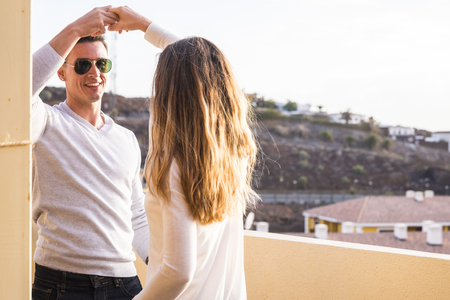 smile and happiness dancing outdoor on the terrace. couple in love and friendship have fun together on the rooftop with mountains viewの写真素材