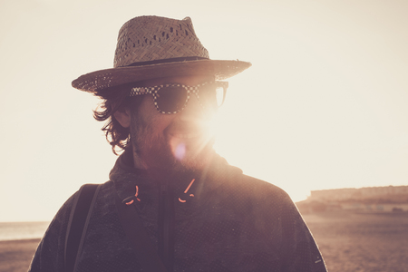 man with straw hat and beard on the beach at sunset looks and smiles and smilesの写真素材