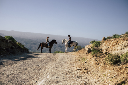 couple of riders and horses together on the road at the mountains. discover and travel the world in alternative lifestyle way. enjoy the nature and feel the silence. westerne concept sceneの写真素材