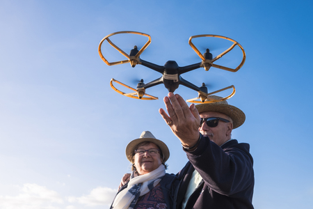 modern technology drone with two elderly senior. Hats and fun with blue clear sky backroundの写真素材