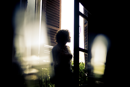 defocused and bokeh for a beautiful woman look outside at the window with nature. romantic scene.の写真素材