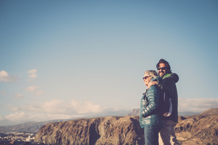 Mother with white hair and a 45 year old son spend time together smiling, surrounded by unspoiled nature. Between sea and mountain hiking and trekking activityの写真素材
