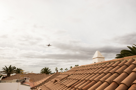 Fly down plane taking off to the airport of Tenerife just near to the roof of some house. People on vacation.の写真素材