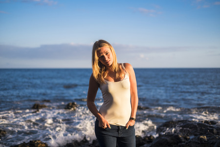 beautiful blonde girl model standing at the beach in front of the ocean in Tenerifeの写真素材