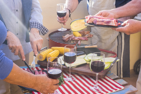 close up with a lot of aged hands prepared meal with barbeque outdoor. fresh food like meal and vegetable and mais pop corn cooked on the flame. group of people in nice activity for elderlyの写真素材