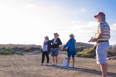 4 seniors spend free time on the beach watching and piloting the droneの写真素材