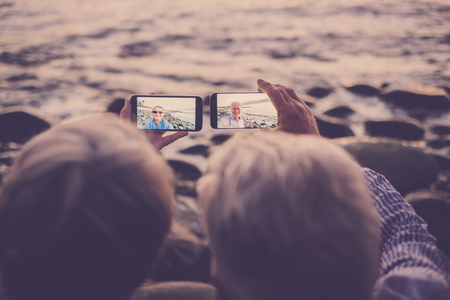 senior couple sitting at the beach taking selfieの写真素材