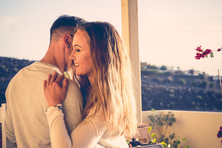 beautiful long hair young caucasian couple dancing and moving on the rooftop with ocean view. beautiful outdoor sun light and nice leisure activity on the terrace. model in love.の写真素材