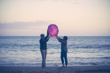 cute woman and middle aged woman having fun in the beach at outdoor. man and embrace her. sand on the backgroundの写真素材