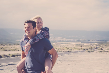 nice caucasian couple in vacation leisure outdoor. enjoy and smile in love together playing and hugging full of lovely thoughts. the man take the lady on his shoulder walking together laughingの写真素材