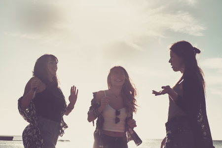 Relationship between three young beauty woman dancing on the beach during a vacation. Sunset time in Tenerife, flare effect and warm filter.の写真素材
