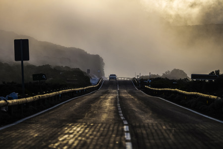 long road for travel concept immersed in the clouds in mountain like fog. misty scene like fire. lights and shadows everywhereの写真素材