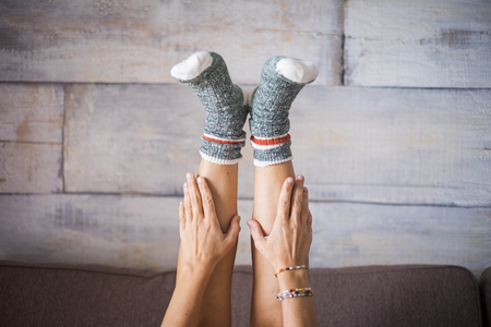 in the middle composition with beautiful woman legs downside with funny and colored socks taken by hands. alternative joy and lifestyle concept for independent middle age femaleの写真素材