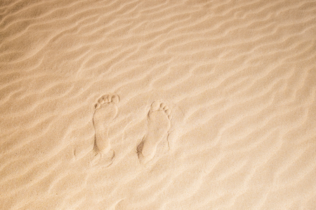 single pair of man or woman footsteps on the virgin sand at the beach in Fuerteventura. Summer concept. Nudism barefoot.の写真素材