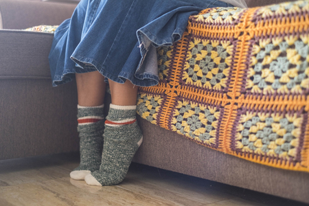 caucasian woman legs and feet wearing a pair of happy and funny socks at home during the winter. light come from window, close up composition. unusual wear and crazy artist conceptの写真素材