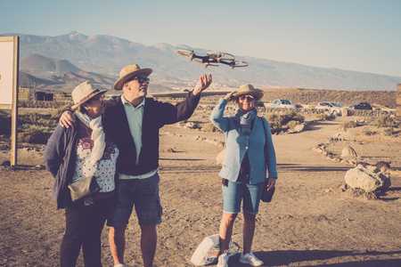 Leisure for seniors man and women looking and touching a flying drone near a parking outdoor in the parks. Curiosity about the object. Learning concept.の写真素材