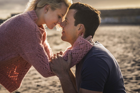closer couple in beautiful love moment together feeling the emotion nose touch nose and hug with passion. sunste light in the background for golden romantic sweet image. tenderness and passionate lover man and woman.の写真素材