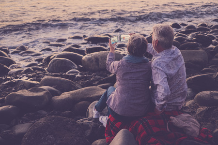 senior man and woman on vacation at the sea taking photoの写真素材