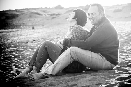 cute man and woman middle aged having fun in love at the beach outdoor. leisure activity and big smile and laugh for the lady. the man embrace her. rocks on the backgroundの写真素材