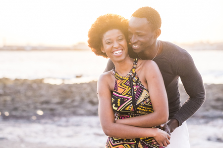 black race african afroamerican couple in relationship or partnership or friendship touching and enjoying the sunset on the beach in vacation outdoor leisure timeの写真素材