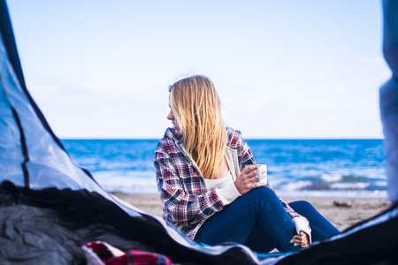 alternative life and vacation concept for blonde cute girl sit down looking at the ocean on the door of her tent. Tenerife locetion.の写真素材