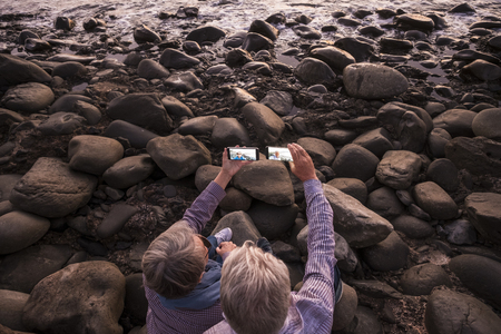 senior couple take photo sitting on the beach at sunsetの写真素材