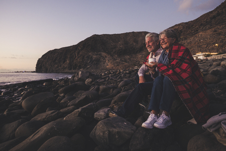 elderly couple sitting at sunset in front of the oceanの写真素材