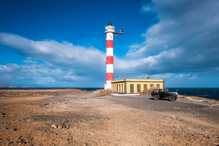 living a dream with a tiny home lighthouse near the coast and the power of the waves. Ocean and sky. Black offroad car parked outsideの写真素材