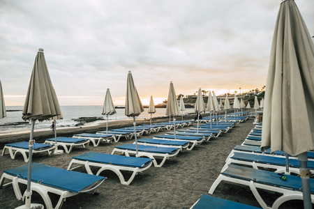 umbrellas and seats in closed business at the beach after a day full of sun and vacation outdoor leisure concept. colors and relaxed time in sunset skyの写真素材