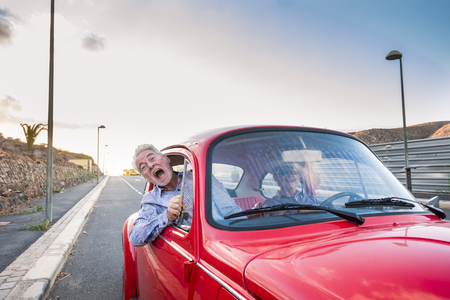 nice beautiful senior adult couple traveling together while the woman drive and the man shout for scare or for craziness. happiness and joy together forever in a perfect couple lifeの写真素材