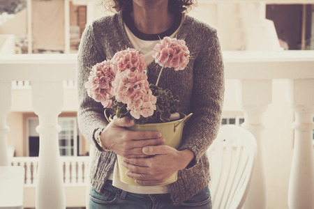 caucasian woman middle age with big vase of flowers outdoor in the terrace with sunlight. romantic bohemien concept hippy lifestyleの写真素材