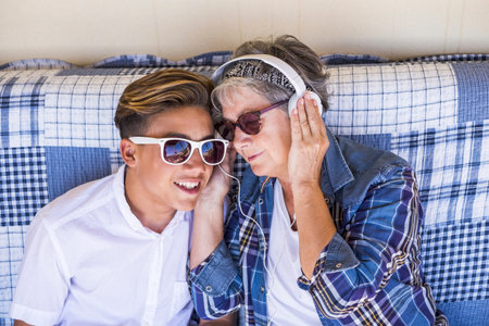 couple young and old grandmother and teenager nephew family time together listen music with...