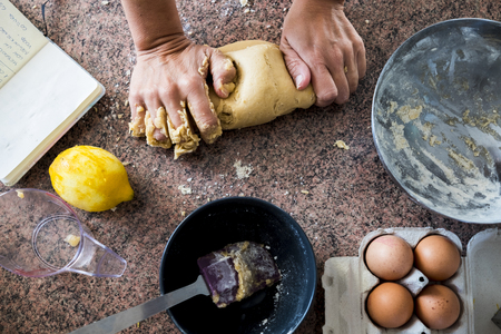 A pair of woman strong hands doing pasta for a cake in the kitchen. Eggs and limon. Taken from above with different point of viewの写真素材