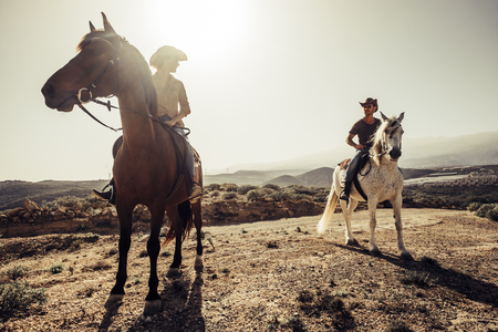 couple of horses and cowboys male and female ride free in the nature at the mountains in tenerife. lifestyle and alternative works or leisure activity concept for man and womanの写真素材