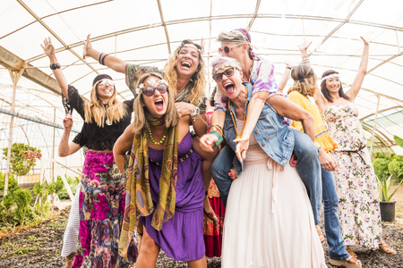 group with many girls caucasian beautiful models have fun together celebrating with colorful dresses and friendship all together. playing carrying on the back and a lot of smiles and laughsの写真素材