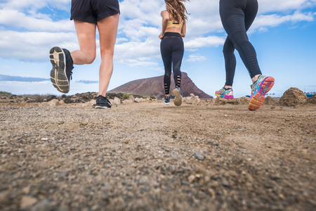 ground poiint of view for three beautiful young girls running and do healthy exercises outdoor near a mountain. scenic outdoor leisure activity in friendship and fitness relatedの写真素材