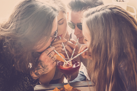 group of caucasian young friends drink all together from one vase with cocktali like sangria. party event celebrating concept in friendship under the sunlight outdoor vacationの写真素材