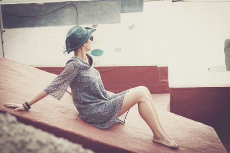 lonely sexy girl in summer dress stay relaxed in outdoor resting activities on vacation. sea place with white walls and vintage colors for holiday concept imageの写真素材