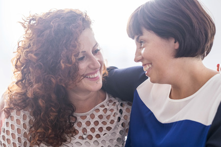 couple of female friends smiling together each other. enjoy friendshiop and relationship. caucasian...