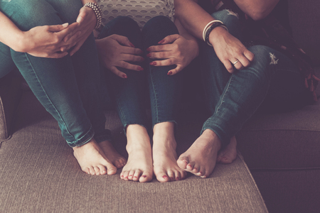 three pair of women feet siting on the sofa at home. vintage brown colors for freidnship and relationship concept between same sex.の写真素材