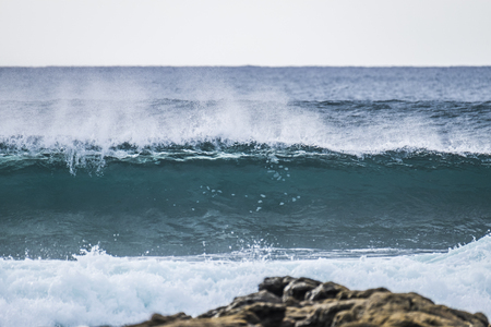 blue power wave with wind in fuerteventura. rocks and water.の写真素材