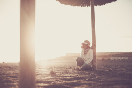 young woman sitting on the beach at sunsetの写真素材